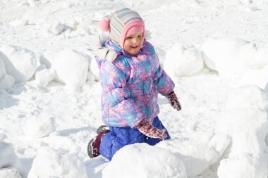 Kış tulumlu küçük tatlı kız kışın karda oynar, seçici keskinleştirme, özel bulanıklık.