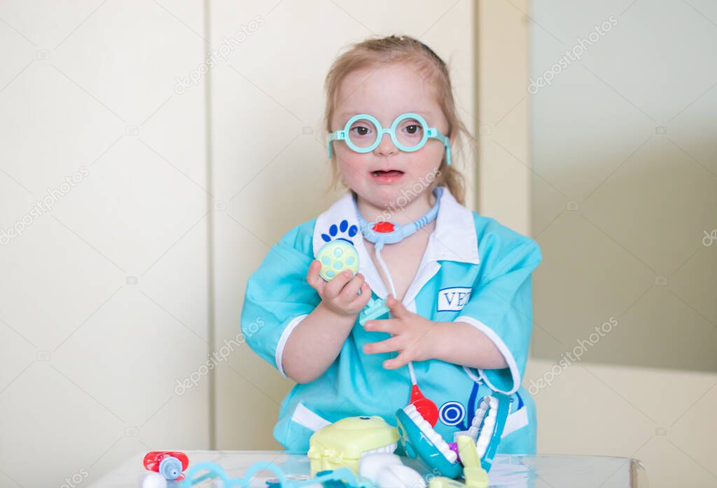 Down syndrome in a little girl, a child in a doctor's costume playing with a doll and with medical instruments, disabled children, genetic mental illness, an extra chromosome in humans.