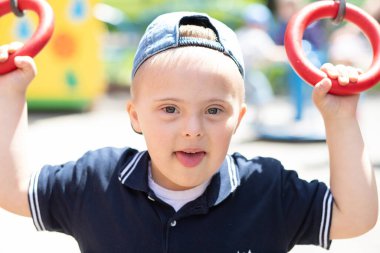 Down sendromlu bir çocuk oyun alanında oynuyor. Engelli bir çocuk, fazladan kromozomu olan bir çocuk..