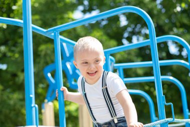 Down sendromlu bir çocuk oyun alanında oynuyor. Engelli bir çocuk, fazladan kromozomu olan bir çocuk..