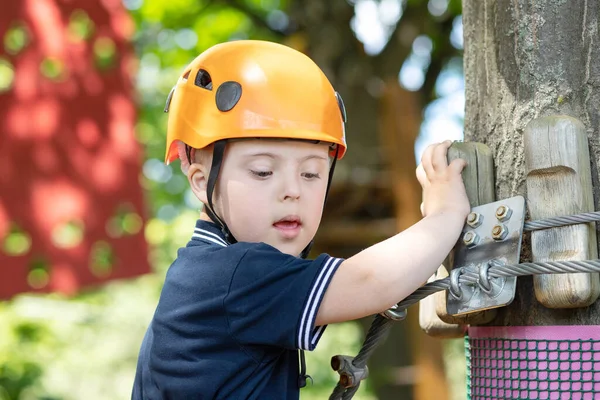 A happy boy with Down syndrome in an orange helmet goes through a difficult sports task, a disabled child, child sports entertainment.
