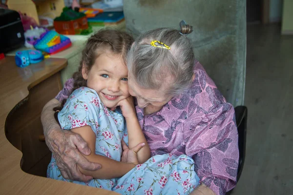 Portrait of an old woman and a little girl, grandmother hugs her granddaughter, family ties, old age and youth, 90 years, wrinkles on an old face, beautiful old age, a woman and a child.