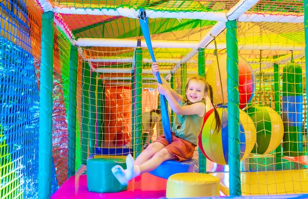 cute girl plays in the play area on background