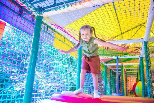 cute girl plays in the play area on background