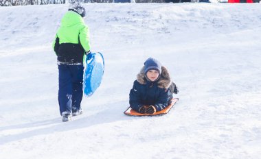 Kışlık giysiler içinde yakışıklı bir çocuğun portresi, anlamlı gözler, parlak yanaklar ve bir okul çocuğunun güzel bir gülümsemesi, bir çocuk kışın karlı dağlarda dinleniyor.