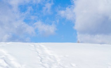 Kış manzarası, masaüstü arka planı, duvar kağıdı, mavi gökyüzü ve karlı tepe, kardaki ayak izleri, seçici odak, kardaki ayak izlerindeki keskinlik, güzel bir arkaplan için özel bulanıklık.