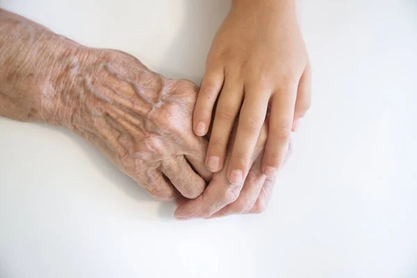 The hands of the child in the hands of the grandmother, the old brownish skin in the elderly woman, motherly love and care.
