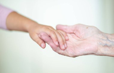Çocuğun elleri büyükannenin ellerinde, yaşlı kadının yaşlı kahverengi teni, anne sevgisi ve bakımı..