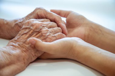 Çocuğun elleri büyükannenin ellerinde, yaşlı kadının yaşlı kahverengi teni, anne sevgisi ve bakımı..