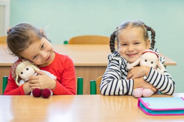 İki güzel kız masada oturuyor, çocuklara ders veriyor, okula geri dönüyorlar, çocuk gelişimi, karantinanın sonu, okuldaki kızlar.