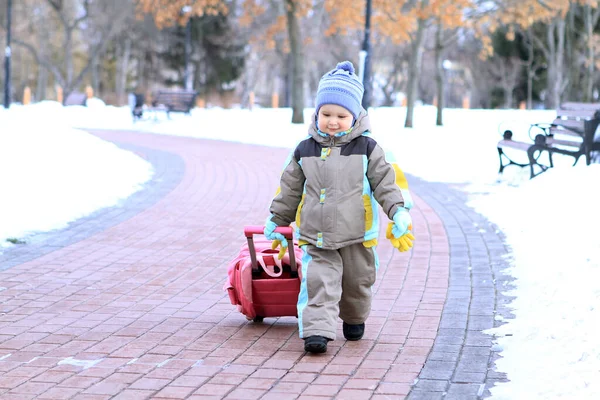 Büyüleyici bir parkta, mutlu küçük bir çocuk dolambaçlı bir yolda ilerliyor, arkasında parlak kırmızı bir araba çekiyor. Etrafındaki ağaçlardan süzülen yapraklar gibi kar zemini kaplıyor..