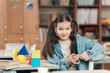 Güneşli bir sınıfta, neşeli bir liseli kız masasında oturuyor, canlı öğrenme araçlarıyla çevrili. Eğitimin neşesini somutlaştıran çalışmalarına daldıkça neşeli ruhu parlıyor..
