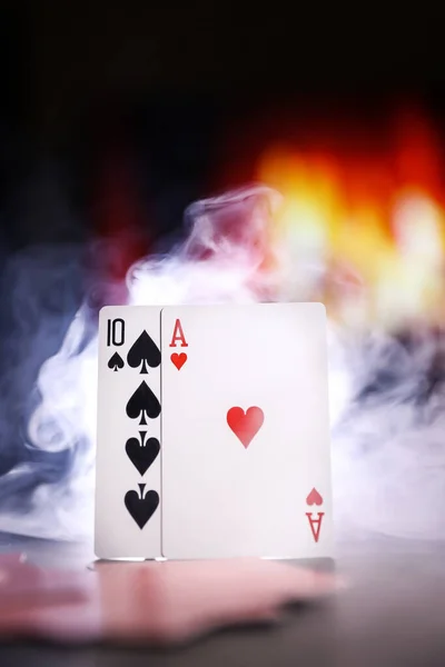 A pair of aces on a deck of playing cards in a smoke against the background of a burning fireplace. Online gambling. Gambling addiction