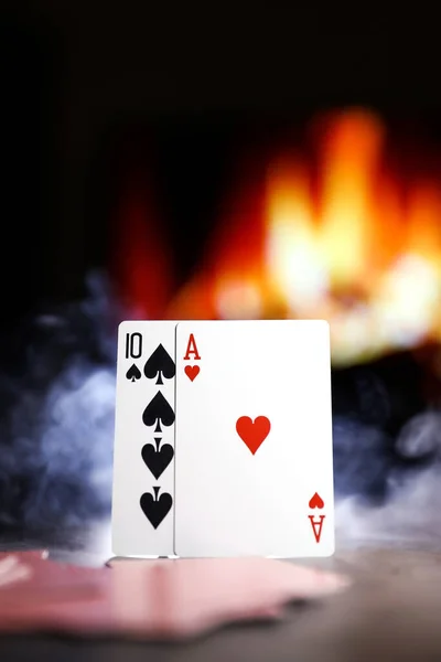 A pair of aces on a deck of playing cards in a smoke against the background of a burning fireplace. Online gambling. Gambling addiction