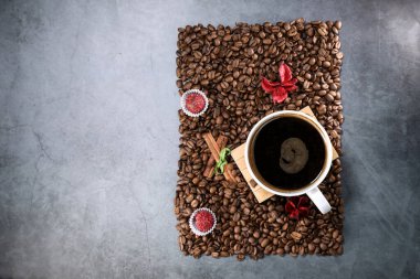 Kırmızı çikolata ve kırmızı çiçekli fotoğraf çerçevesi şeklinde kahve çekirdekleri ile dolu beyaz bir fincanın düz manzarası vardı. Sabah espresso. Kahve kupası..