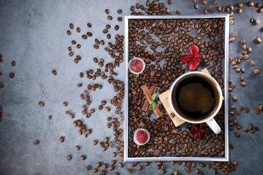 Kırmızı çikolata ve kırmızı çiçekli fotoğraf çerçevesi şeklinde kahve çekirdekleri ile dolu beyaz bir fincanın düz manzarası vardı. Sabah espresso. Kahve kupası..