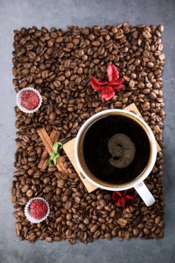 Kırmızı çikolata ve kırmızı çiçekli fotoğraf çerçevesi şeklinde kahve çekirdekleri ile dolu beyaz bir fincanın düz manzarası vardı. Sabah espresso. Kahve kupası..