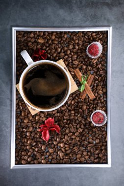 Kırmızı çikolata ve kırmızı çiçekli fotoğraf çerçevesi şeklinde kahve çekirdekleri ile dolu beyaz bir fincanın düz manzarası vardı. Sabah espresso. Kahve kupası..