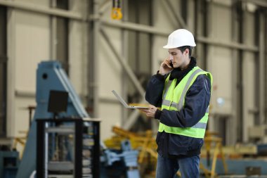  Bir adamın portresi, iş kıyafetleri içinde dizüstü bilgisayar ve telefon taşıyan bir fabrika mühendisi, helikopter üreticisinin çalışma sürecini kontrol ediyor..