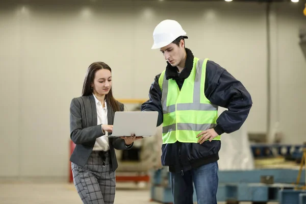 Beyaz bir şapka ve iş elbisesi içinde kadın bir fabrika müdürünün portresi ve iş elbiseli bir fabrika mühendisi. Helikopter imalatçısının çalışma sürecini kontrol etmek.