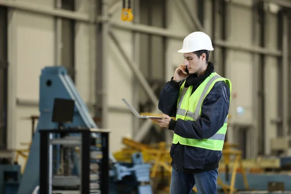  Bir adamın portresi, iş kıyafetleri içinde dizüstü bilgisayar ve telefon taşıyan bir fabrika mühendisi, helikopter üreticisinin çalışma sürecini kontrol ediyor..