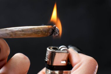 El ele tutuşarak sigara. Siyah arka planda izole edilmiş esrar içmek. Tıbbi kullanım.