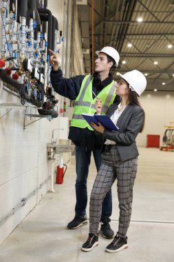 Beyaz bir şapka ve iş elbisesi içinde kadın bir fabrika müdürünün portresi ve iş elbiseli bir fabrika mühendisi. Üretimdeki çalışma sürecini kontrol etmek.