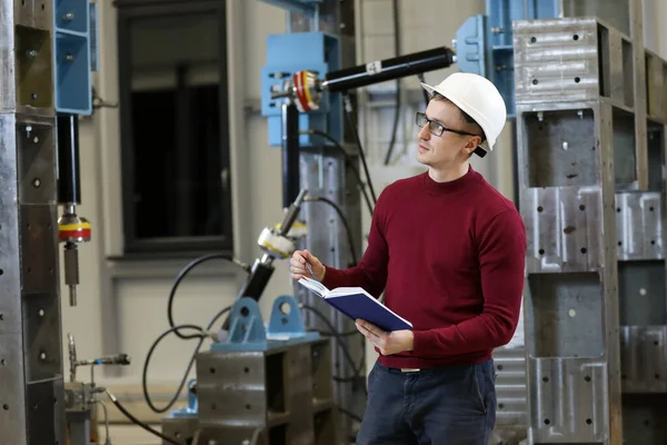 Beyaz şapkalı ve kırmızı kazaklı bir fabrika müdürünün portresi helikopter üreticisinin çalışma sürecini kontrol ediyor..