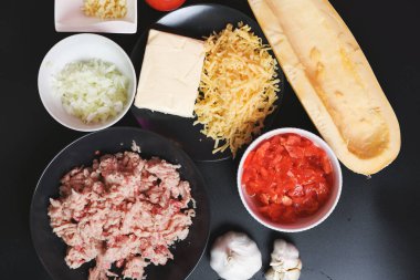 Ahşap mutfak masasında pişirmek için taze sebzeler. Soğan, sarımsak, kırmızı domates, sarı kabak, mutfak masasında taze et ve peynir..