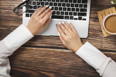Hippi ahşap çalışma alanı, ofis masası manzarası. Dizüstü bilgisayarda çalışan kadın ellerini düz bir şekilde görüyordum. Ofis işleri. İş toplantısı. Kahve molası.