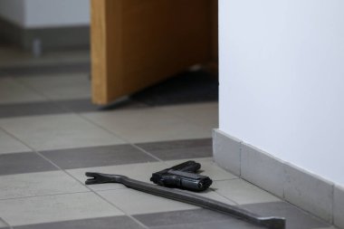 Siyah silah ve levye yere. Hırsız dairelere zorla girmiş. Hırsız evden bir şeyler çalıyor.