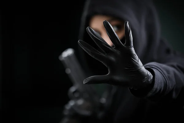 Thief broke into the apartment. House robbery by woman in a black jacket and black mask black gun and crowbar. Burglar in a mask. Thief in a mask trying to break into other people's house.