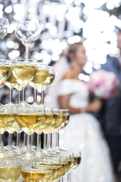 Champagne tower in front of bride and grooms in a wedding ceremony. Champagne glasses.