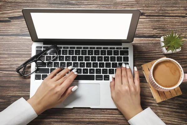 Top view of hipster wooden workspace, office table desk. Flat lay view of woman hands working on a laptop. Office work. Business meeting. Coffee break.