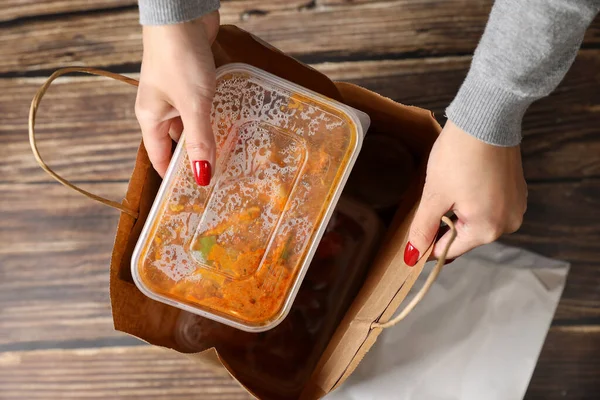 Dişi eller torbadaki yiyecekleri plastik torbalara doldurur. Yemeği evde sipariş et. Yemek teslimatı.