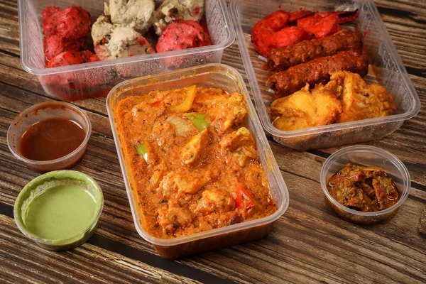 Top view of traditional Indian food in a plastic box on a wooden table. Indian fast food delivery at home. Eat at home.