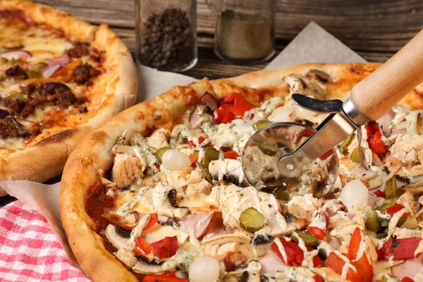 woman\'s hand cuts the pizza with a pizza knife. Home made pizza. Home delivery.