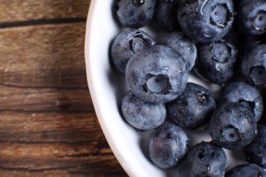Tahta masadaki yabanmersini dolu beyaz tabağın üst görüntüsü. Meyve vitamini.