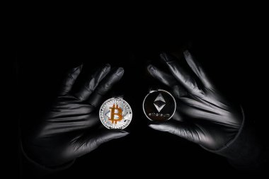 Siyah arka planda Bitcoin ve Ethereum madeni para tutan siyah eldivenler. Uluslararası hacker şifreli para birimlerinizi çalmaya çalışıyor. Zincirleme güvenlik.