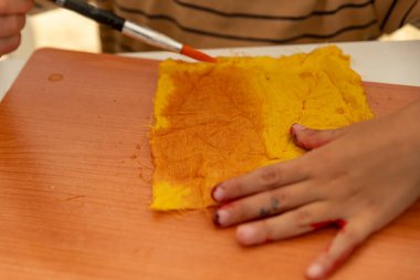 Çocuk Elleri Sarı Kumaşı Fırçayla Boyuyor, Yaratıcı Sanat Atölyesi Etkinliği. Yüksek kalite fotoğraf