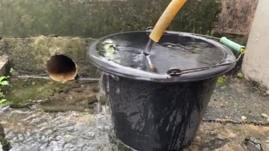 Temiz su hortumdan mavi kovaya akar. Su bir kovaya dökülür. Fıçıdaki su bir hortumdan toplanır.