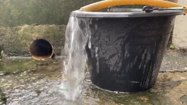 Temiz su hortumdan mavi kovaya akar. Su bir kovaya dökülür. Fıçıdaki su bir hortumdan toplanır.