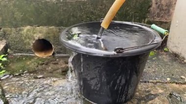 Temiz su hortumdan mavi kovaya akar. Su bir kovaya dökülür. Fıçıdaki su bir hortumdan toplanır.