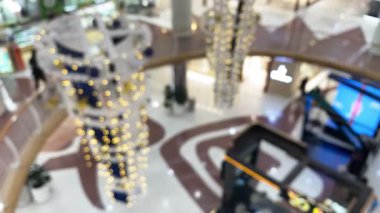 Bulanık insanlar modern bir alışveriş merkezinde yürüyor soyut bir şehir perakendecisi ortamı yaratıyor ve Noel 'i kutlamak için Bokeh dekoratif ışıklarla karşılıyorlar..