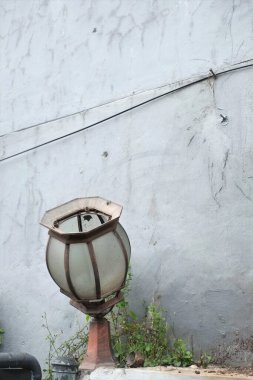 Old broken street or garden lamp on a high leg with a broken shade to scatter light.Closeup shot of a broken garden lamp