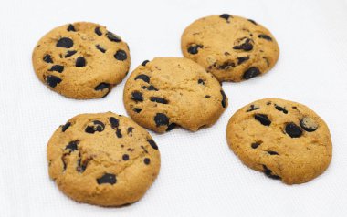 Beyaz kumaş üzerinde çikolata parçacıkları olan tereyağlı kurabiyeler.