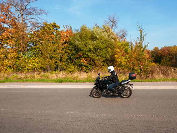 Motorradfahrer in Bewegung. Radfahrerin auf schwarzem Motorrad im Straßenverkehr auf einer Landstraße. — Stockfoto