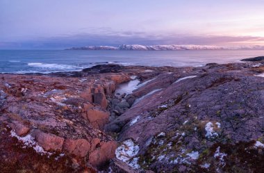 Kutuplardaki beyaz karlı dağlarla muhteşem bir gün doğumu manzarası. Barents Denizi kıyısında bir vadisi ve pelerini olan harika bir dağ manzarası. Teriberka