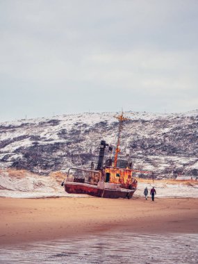 Kıyıdaki bir fırtına tarafından terk edilmiş eski paslı bir balıkçı teknesi. Gemi mezarlığı, Barents Denizi kıyısındaki eski balıkçı köyü, Kola Yarımadası, Teriberka, Rusya.