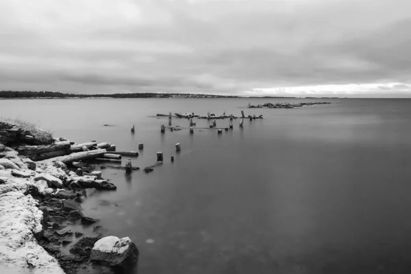Black and white minimalistic landscape with an old ruined pier in the Arctic. Long exposure.